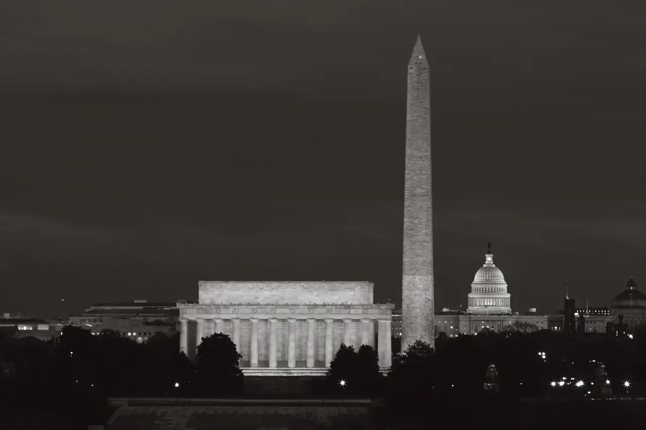 The Lincoln Memorial, the Washington Monument and the Capitol dome at night, in black and white.